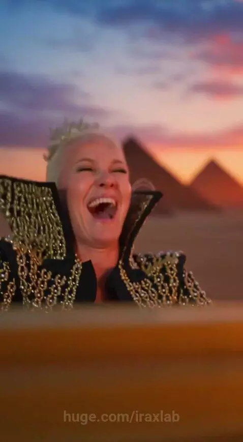 Woman with crown playing golden grand piano in desert with pyramids and colorful sunset.
