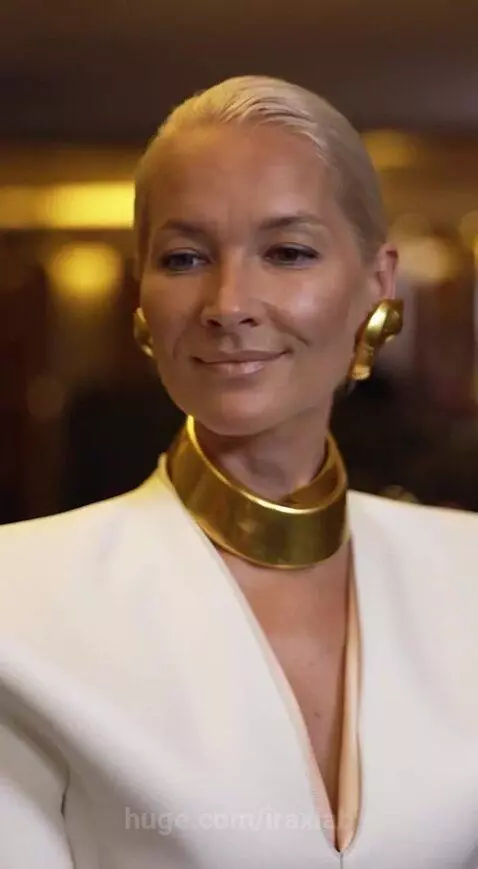 Mark Cuban in a suit jacket and purple shirt asking a woman in a white dress and black corset for an autograph.