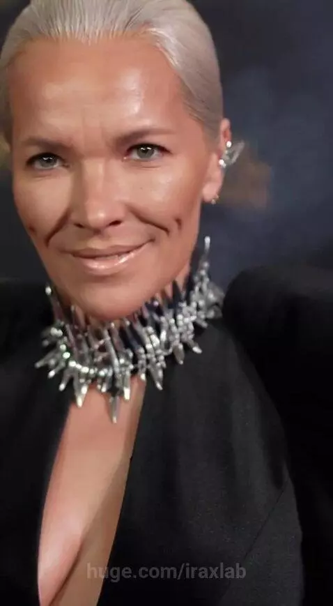 Woman in black velvet gown with metallic embellishments, her face detaches to reveal a robotic head with sparks.