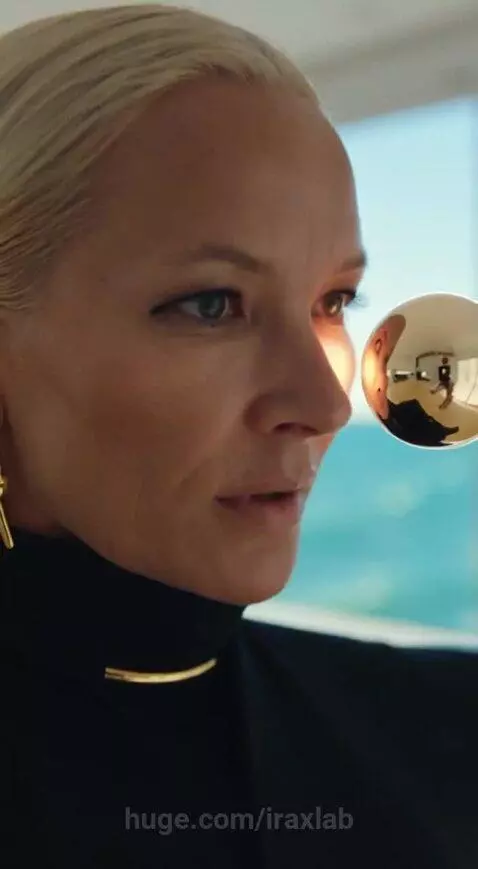Blonde woman in black outfit watches as a golden sphere forms an intricate golden armor suit around her.