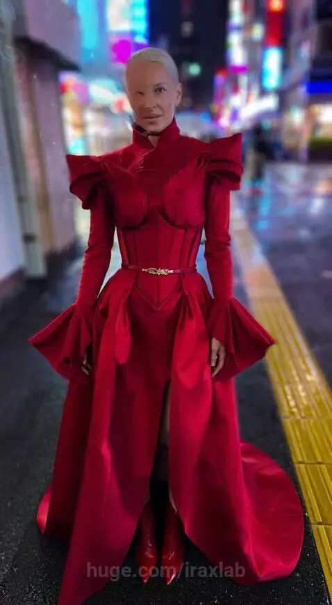Woman in red dress on city street at night, her head detaches revealing robotic components, smoke and sparks emit.