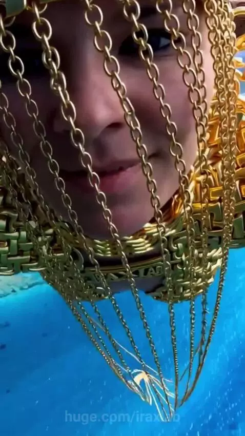 Woman in a golden armor-like costume with a helmet skydiving over a turquoise ocean.