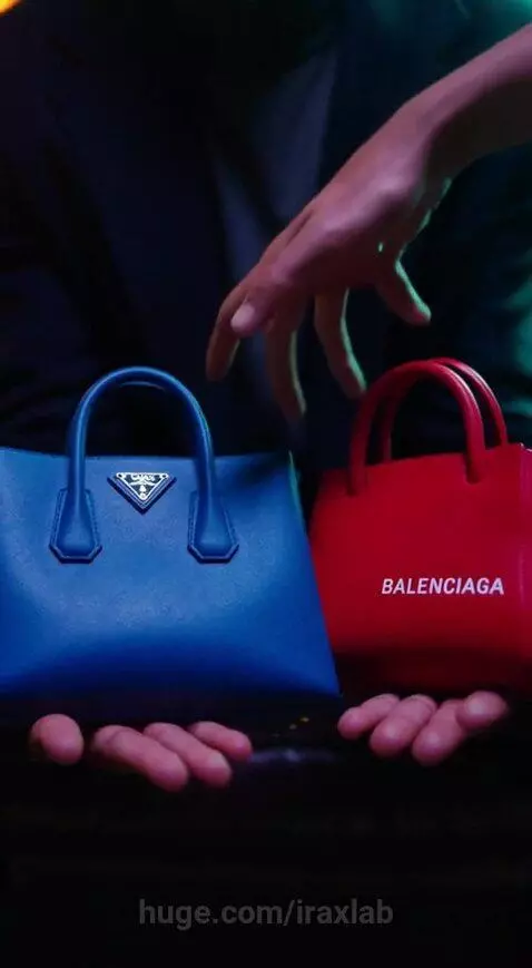 Man in dark coat holding blue Prada and red Balenciaga bags under dramatic green and yellow lighting.
