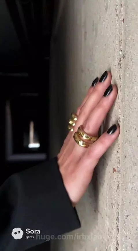 Woman with blonde hair and shoulder pads walks through a concrete corridor and opens a rusty metal door into a dark bunker.