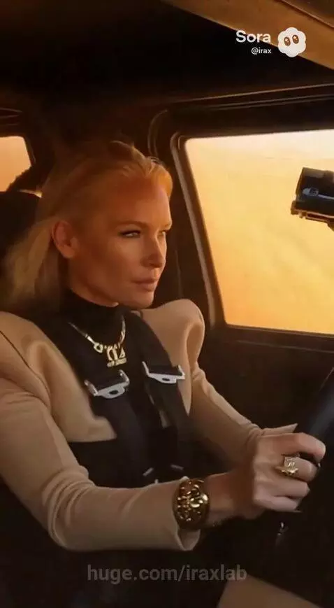 Modified off-road vehicle driving through a desert sandstorm, kicking up sand.