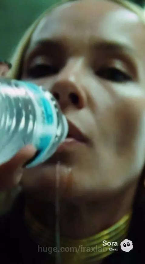 Woman in black blazer and gold jewelry picks sushi from a grocery store cooler.