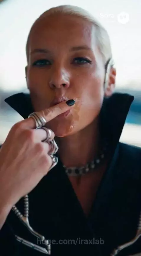 Woman in a striking black coat with silver embellishments eating a turkey leg on an escalator.