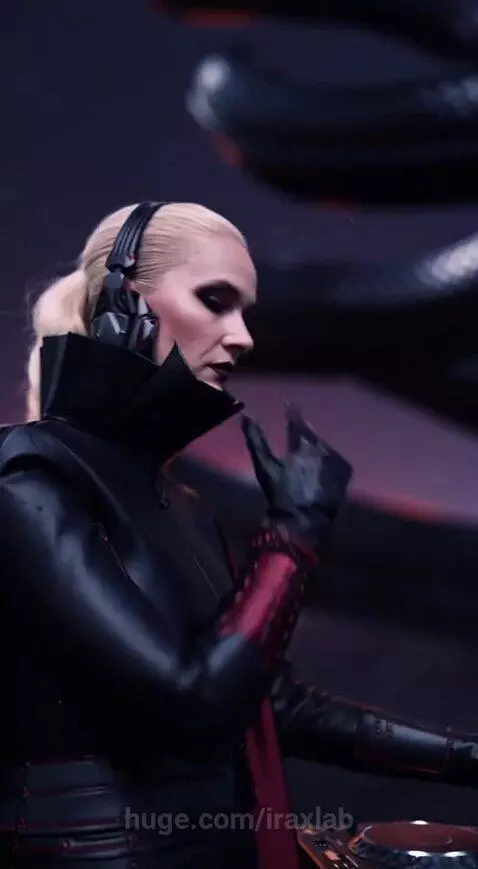 DJ in a black leather jacket and headphones adjusts a mixer with glowing purple lights, with a giant snake and red moon in a desert.