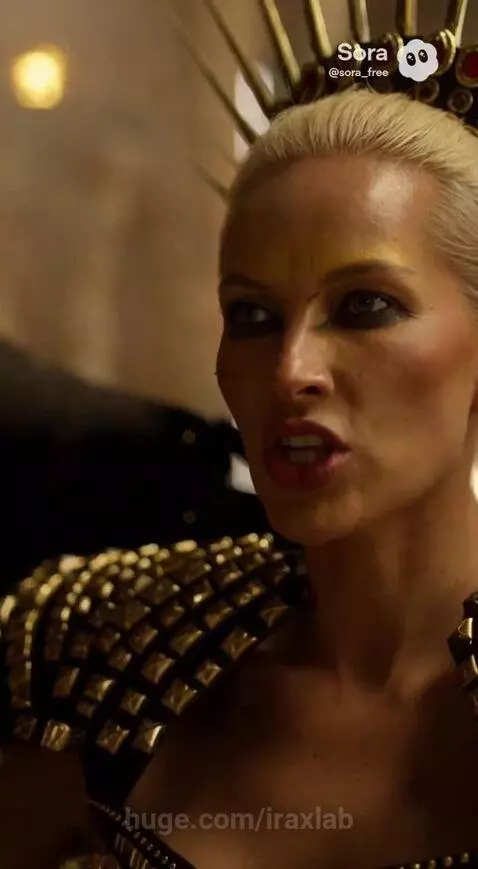 A powerful queen with black wings and a gold crown sits on a throne in an ancient temple, commanding men operating a mechanism.