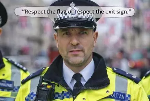 Three UK police officers in uniform stand on a street decorated with Union Jack flags. One officer points forward.