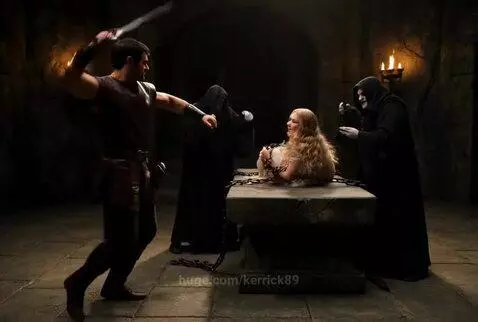 A warrior hero with a sword rescues a woman chained in a stone chamber from hooded figures performing a ritual.