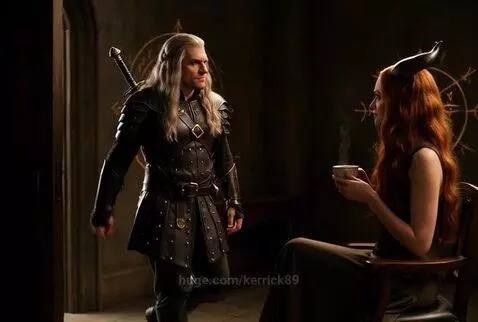 Fantasy warrior with yellow eyes and armor approaches a horned woman with yellow eyes offering coffee.