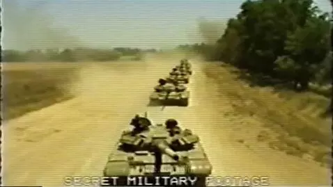1980s Soviet VHS footage of a long convoy of T-72 tanks moving down a dusty rural road, kicking up dust.