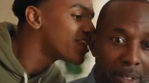 Young man whispers to older man, who reacts with exaggerated joy and a funny dance for Sharon's birthday.