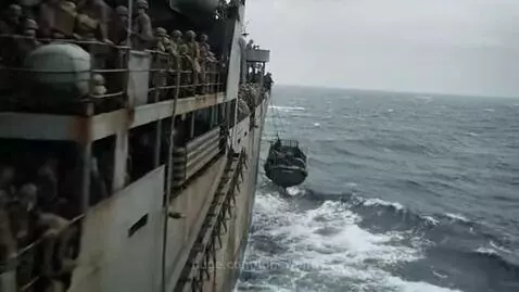 Cinematic drone shot of a large WW2 troop transport ship at sea, decks filled with soldiers, with a landing craft being lowered.