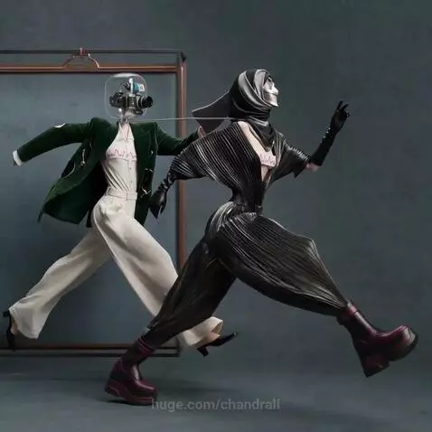 Two stylized humanoid figures, one with a camera for a head, in avant-garde fashion, connected by a wire, on a reflective surface.