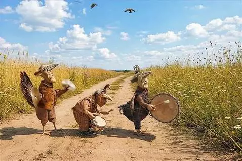 Three anthropomorphic bird puppets playing musical instruments in a sunny field.