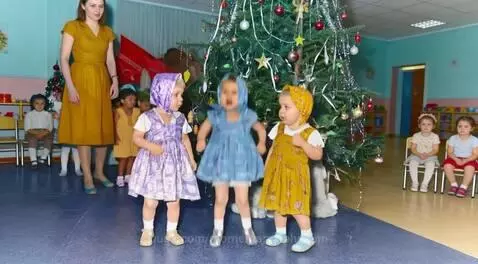 A young girl in a blue dress transforms into a Snow Maiden in front of a Christmas tree, surprising onlookers.