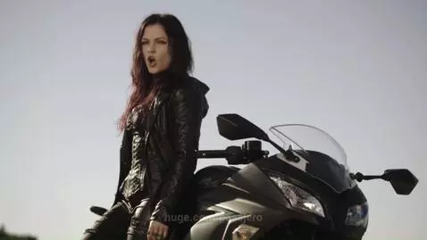 Rock band Anthems for the Dead performing in a warehouse, with a female singer on a motorcycle.