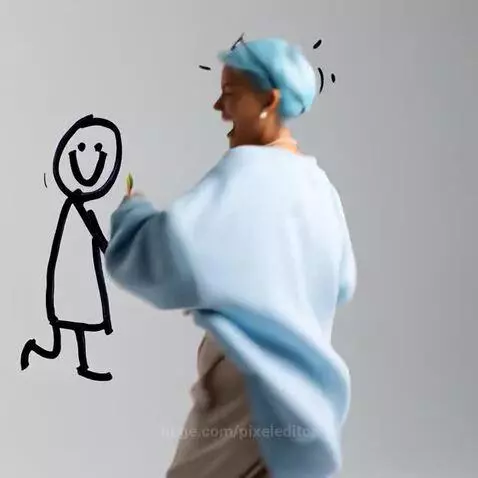 Woman in blue sweatshirt and beige pants laughing while holding a lollipop, playing with a stick figure drawing.