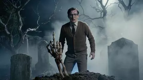 Man in graveyard at night, shocked as a skeletal hand rises from the dirt and extends its middle finger.
