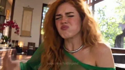 Woman with red hair making a sour face then a happy face while eating sushi.