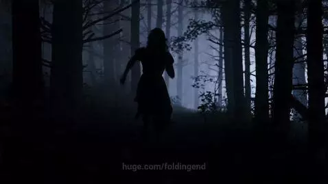 Woman praying with dirt on her face, a cross necklace visible, in a dark, foggy forest setting.