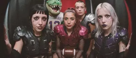 Women in revealing uniforms playing American football with surreal mascots and dramatic lighting.