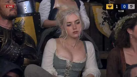 Woman in green corset and blonde updo at a historical fantasy event with a crowd in the background.