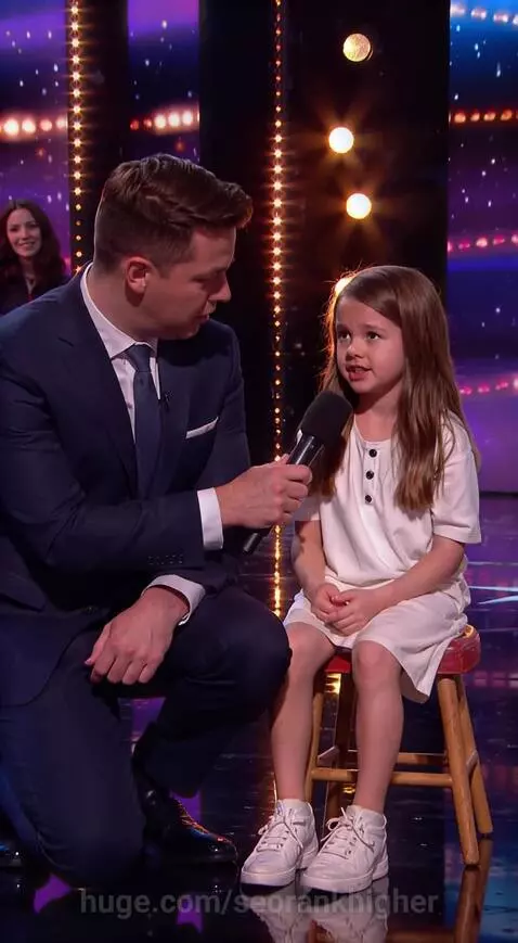 Man interviewing a young girl on stage about her parents' acting jobs. She reveals they are in 'Wrong Turn'.