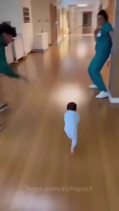 Newborn baby crawling quickly down a hospital hallway, with parents and nurse playfully chasing.