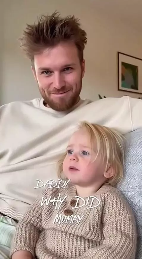 Father with beard smiling at his young daughter sitting on a couch, sharing a funny conversation.