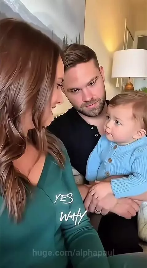 A baby sits with parents in a living room, with a voiceover humorously protecting his dad.