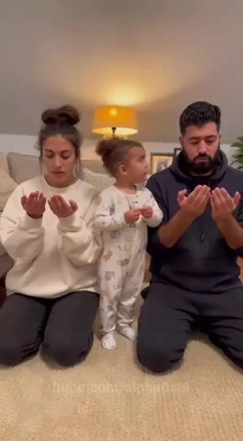 Child in pajamas kneels with parents, praying for money and saying "Daddy is broke."
