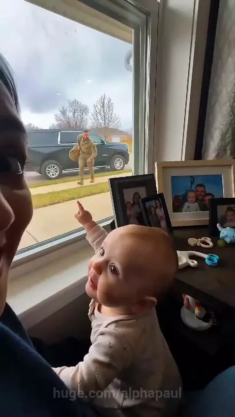 Baby excitedly running into the arms of a soldier dad returning home, mother watches emotionally.