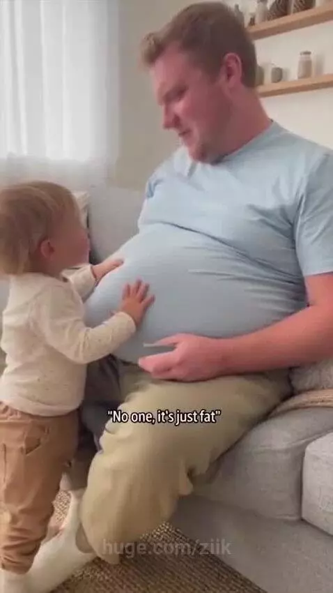 Man with a large belly smiling as a toddler touches his stomach and asks if it's a baby.