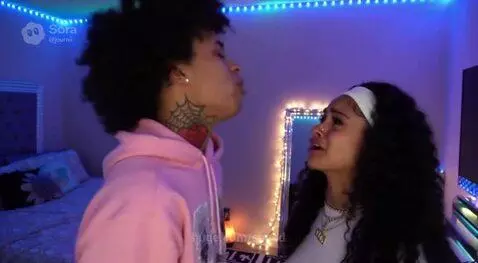 Young couple arguing emotionally in a bedroom with blue string lights, woman is crying.