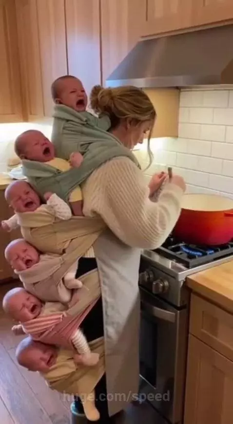 Woman in kitchen apron stirring pot with six distressed babies attached to her in carriers.