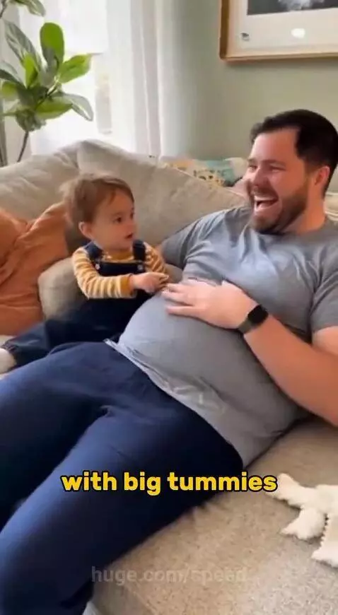 A child in overalls points at a man's belly and asks if he has a baby inside.