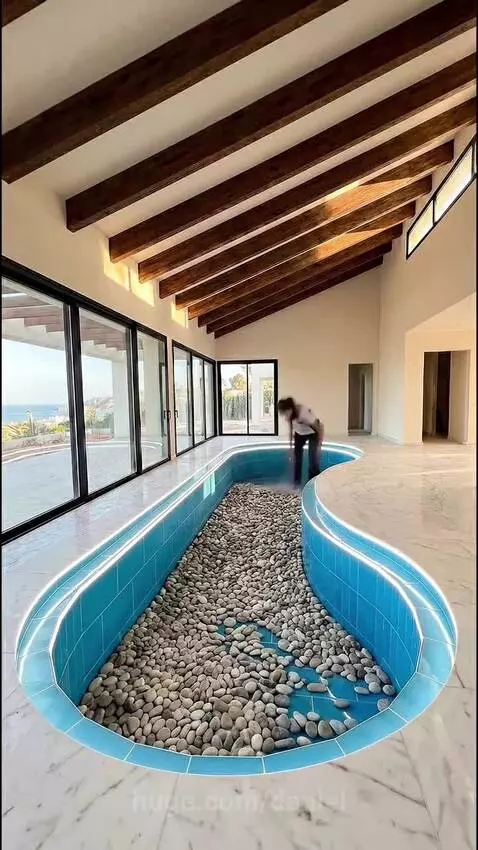 Indoor living room with a transformed S-shaped pool into a decorative aquarium with coral and treasure chests.