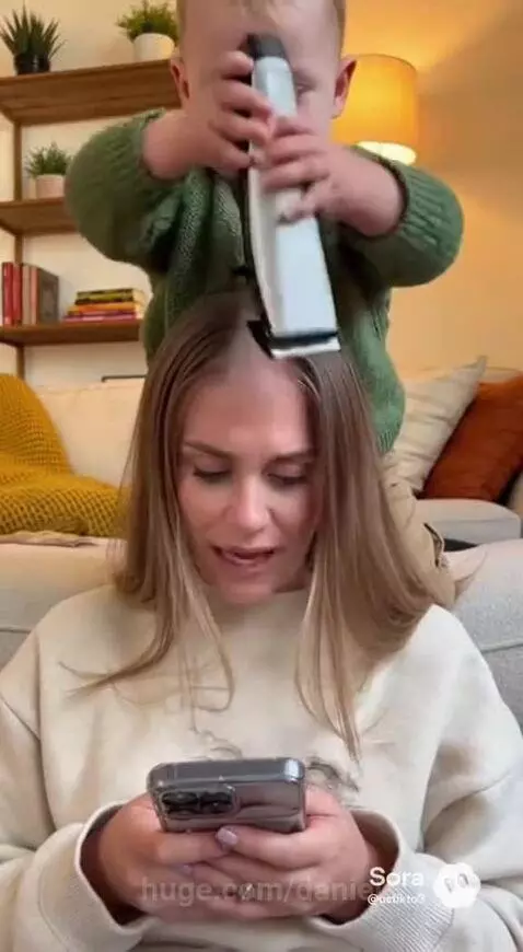 Child with electric clippers shaving a strip of hair from a surprised woman's head.