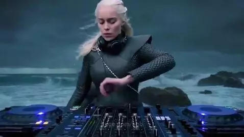 Woman resembling Daenerys Targaryen with headphones DJing by a stormy ocean.