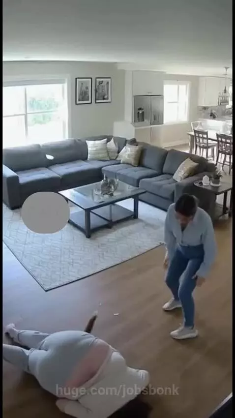 Woman falling on the floor after tripping over an orange cat, with another woman rushing to help.