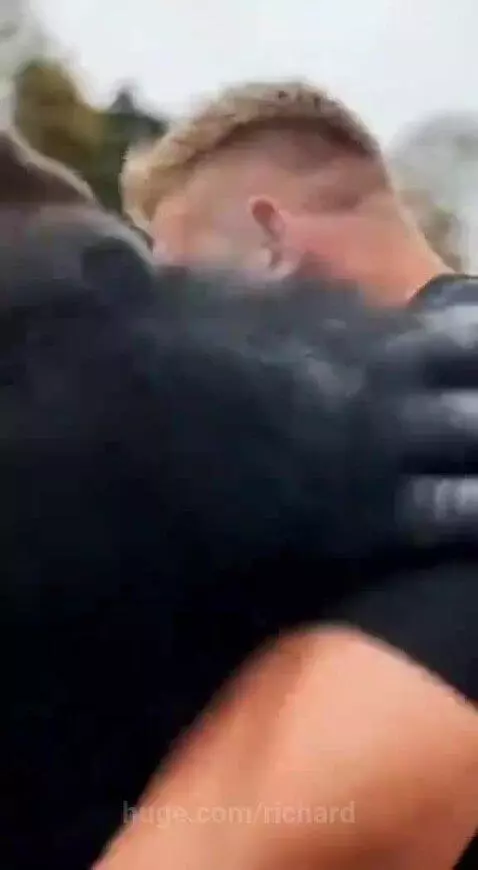 A person in a gorilla suit delivering a powerful slap to a muscular man during a contest.
