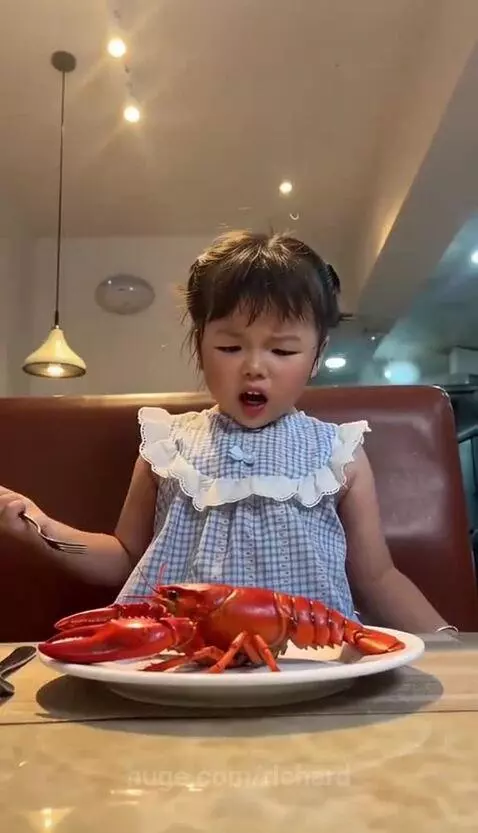 A young girl crying after a lobster sprayed her face in a restaurant, with a man looking surprised.