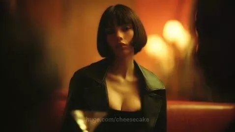 Woman with bob haircut and leather jacket holding a martini in a dimly lit restaurant.