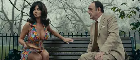A woman in a colorful dress and a man in a suit sit on a park bench, engaged in a serious discussion.
