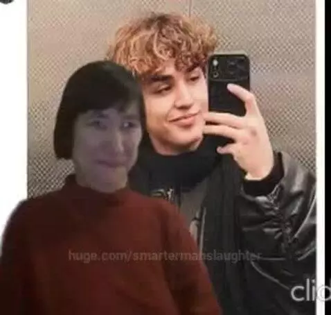 Couple taking a selfie in an elevator, woman with short dark hair and red turtleneck, man with curly brown hair, both smiling.