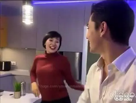 Couple dancing playfully in a modern kitchen, smiling and interacting.