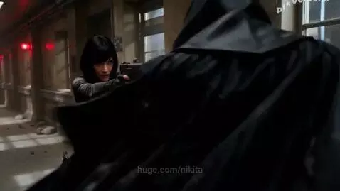 Ada Wong in tactical suit firing a handgun in a dark, damaged hallway with flashing red lights.
